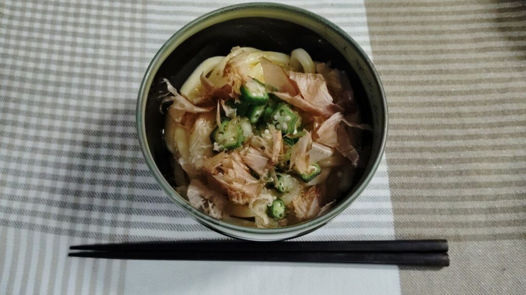 ゆでうどんにたまごを絡め、オクラ、かつお節をトッピング。