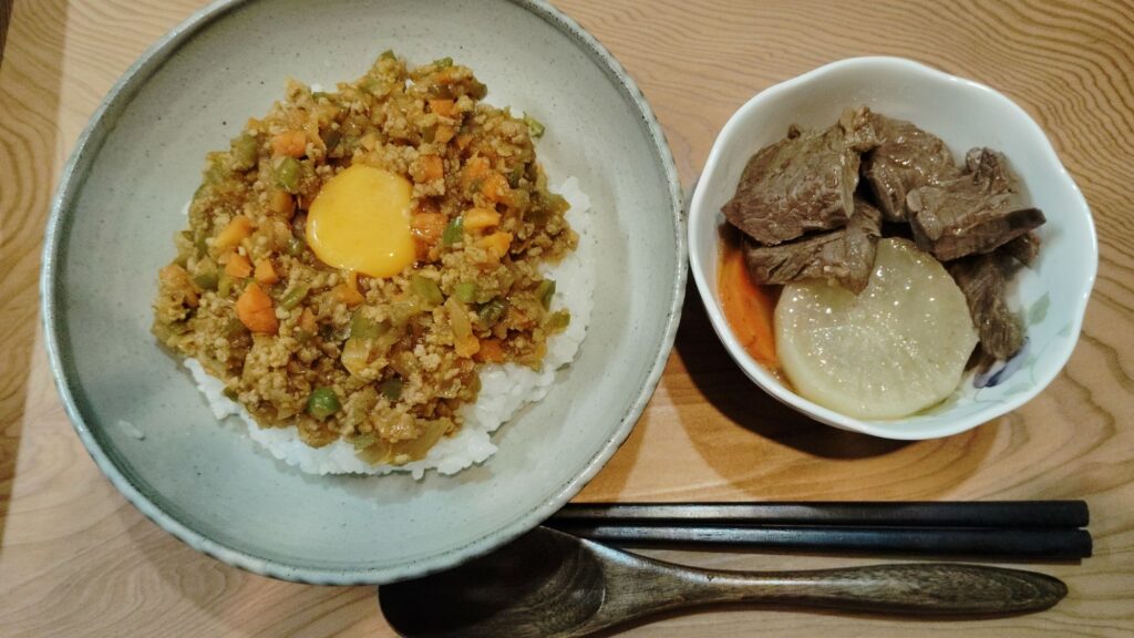 ドライカレー(卵黄のせ)。牛肉と大根・人参の煮物。