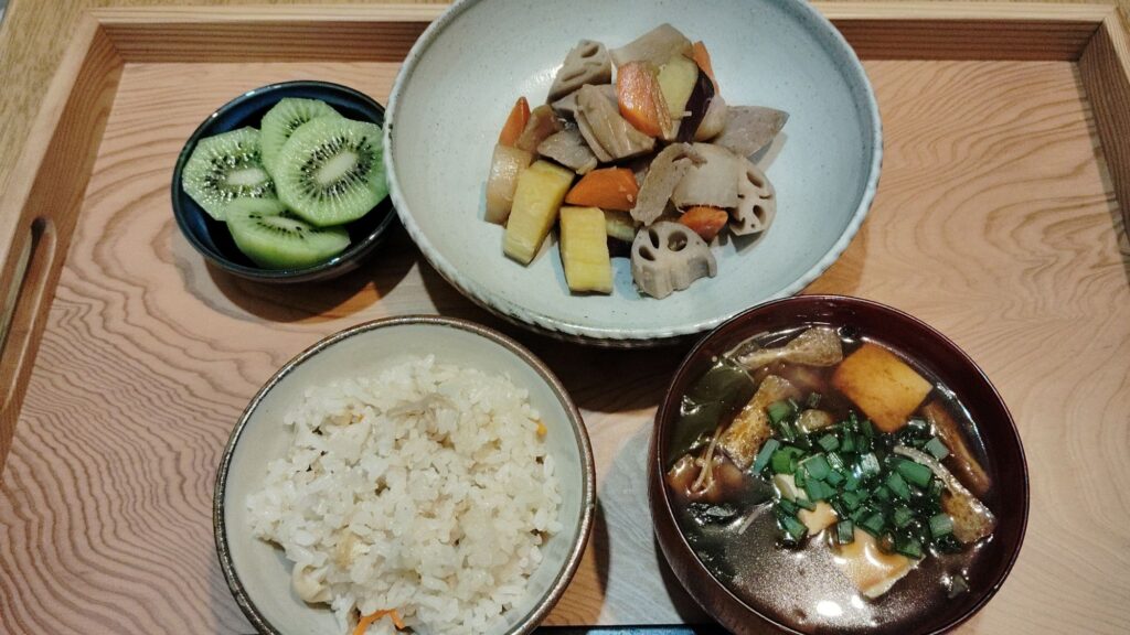炊き込みご飯(人参、えのき、あげ)。みそ汁(わかめ、ほうれん草、とうふ、あげ、ねぎ)根菜の煮物(れんこん、こんにゃく、大根、人参、さつま芋)。キウイ。
