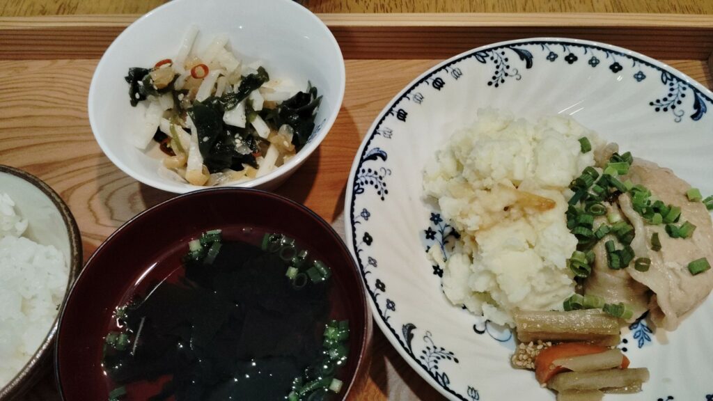 ごはん。豚肉生姜焼き(ねぎ)。ポテトサラダ。ごぼうと人参の煮物。大根とクラゲの和え物(わかめ)。すまし汁(わかめ、ねぎ)。