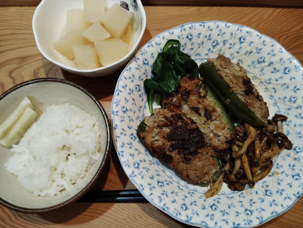 ごはん、たくあん。ピーマンの肉詰め、しめじソテー、ゆで小松菜。大根の煮物。
