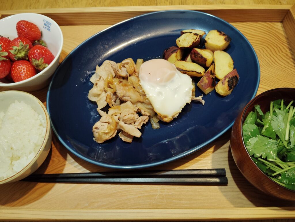 ごはん。豚肉と玉ねぎの生姜焼き。目玉焼き。焼きさつまいも。澄まし汁(三つ葉、ワカメ)。いちご。