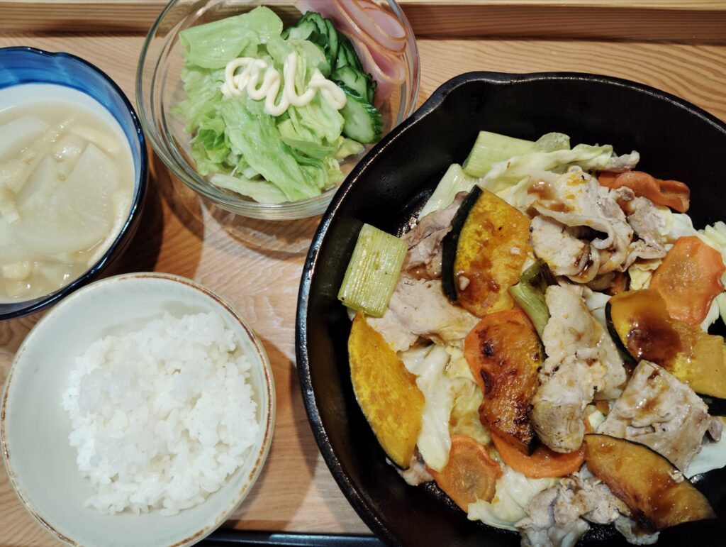 ご飯。豚肉と野菜のスキレット焼き（かぼちゃ人参キャベツ長ネギ）。サラダ（レタスきゅうりハム）大根とあげの煮物。