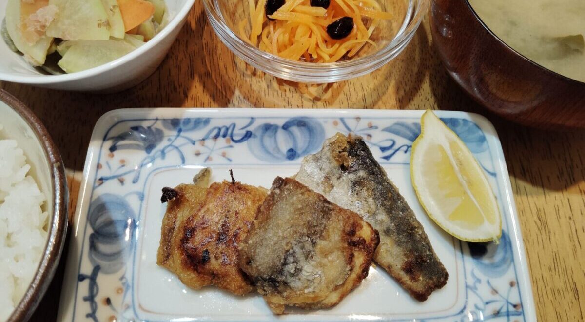 さわらの竜田揚げ、レモン。大根、人参きんぴら。にんじんラぺ、黒豆煮。ごはん。みそ汁（大根、ごぼう、ワカメ）