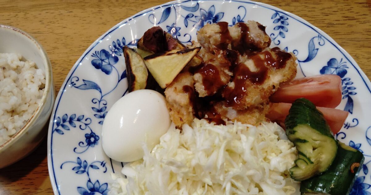 玄米ご飯。鶏胸肉のチキンカツ、千切りキャベツ、トマト、キュウリのポン酢漬け、ゆで卵、さつま芋の素揚げ。