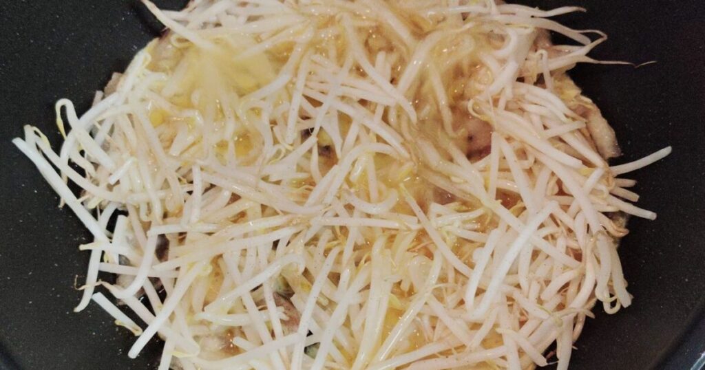 もやしの上に溶き卵を回しかけた様子